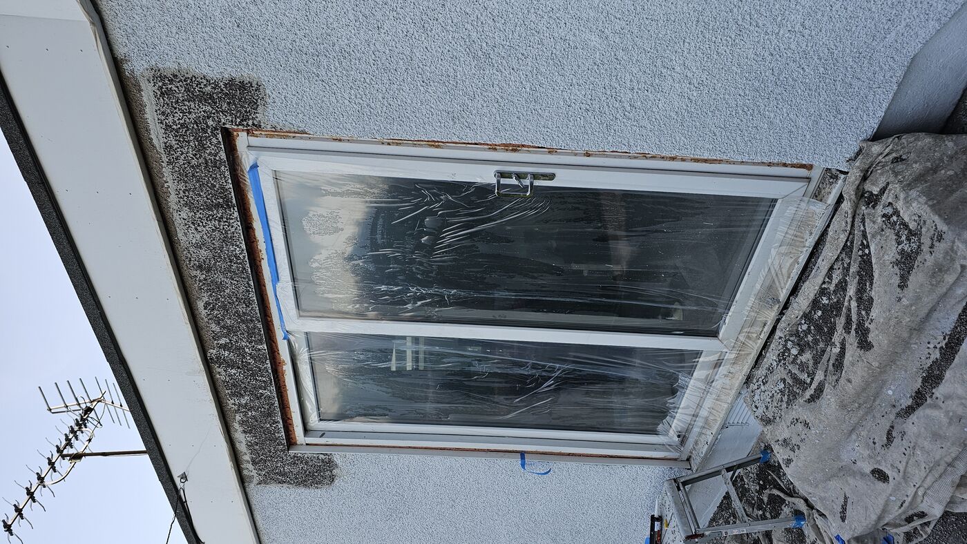 Dark aggregate basecoat applied — wall masked and protected